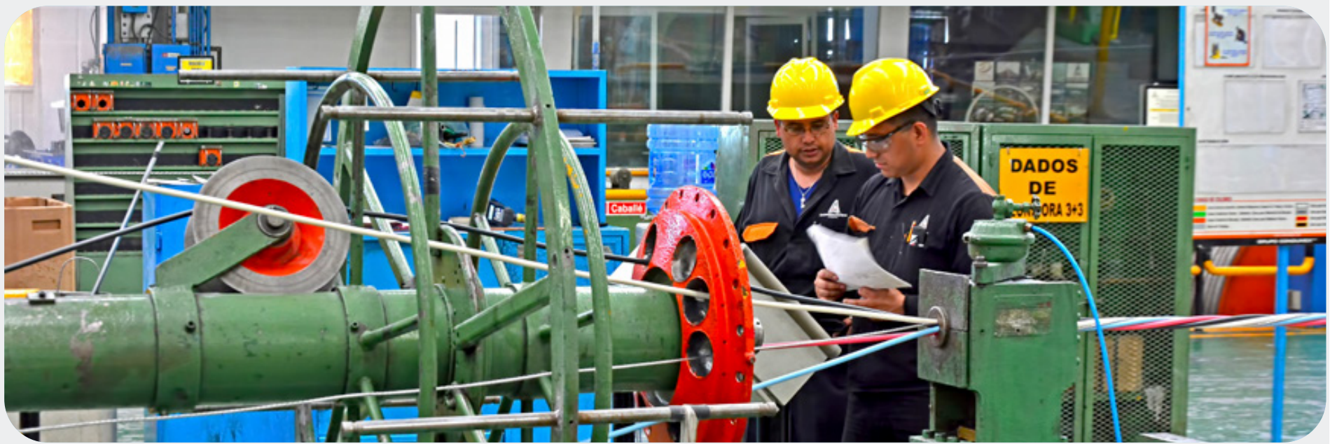 Operadores revisando maquinaria de manufactura de cables